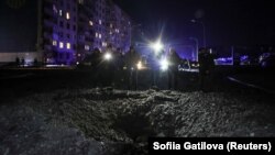 Люди стоять біля кратера, що з'явився після удару російського безпілотника в Харкові, Україна, 30 січня 2024 року