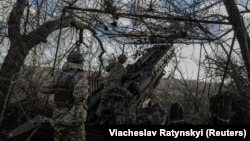 Українські військовослужбовці готують гаубицю М777 до стрільби у бік російських військ біля прифронтового міста Мар’їнка, 26 грудня 2023 року