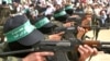 Membrii grupării militante Hamas mărșăluiesc cu puști AK 47 în timpul unui miting în tabăra Bureij din Fâșia Gaza, pe 5 martie 2004.