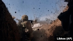 Un soldat ucrainean trage cu un lansator de grenade pe linia frontului în timpul unei bătălii cu trupele rusești lângă Bahmut, pe 24 martie.