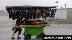 An Afghan vendor pushes a cart of footwear through a street as it rains in Kabul on May 23.