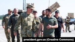 Президент України Володимир Зеленський (праворуч) у День Повітряних сил ЗСУ під час огляду сучасних зразків зброї та військової техніки, які перебувають на озброєнні українських захисників неба, 6 серпня 2023 року. На задньому плані світлини – американський ЗРК Patriot