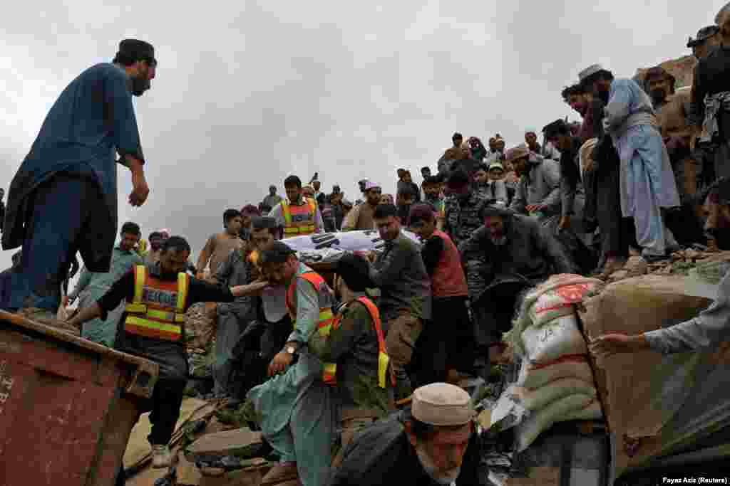 People carry the body of a victim killed in the landslide. Officials said more than 100 firefighters and rescuers were taking part in the operation to save truck drivers and other people who were trapped by the debris. 