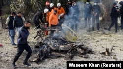 Rescue workers and police officers gather at the site of a suicide car bombing in Islamabad on December 23.