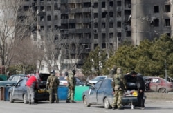 Soldați ai trupelor pro-ruse verifică mașinile în Mariupol, 20 martie 2022.