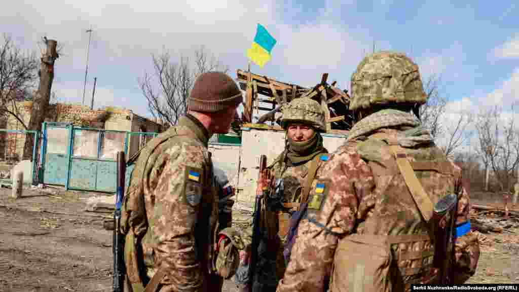 Українські військові розмовляють один з одним у нещодавно звільненому селі Лук'янівка Київської області, 27 березня 2022 року