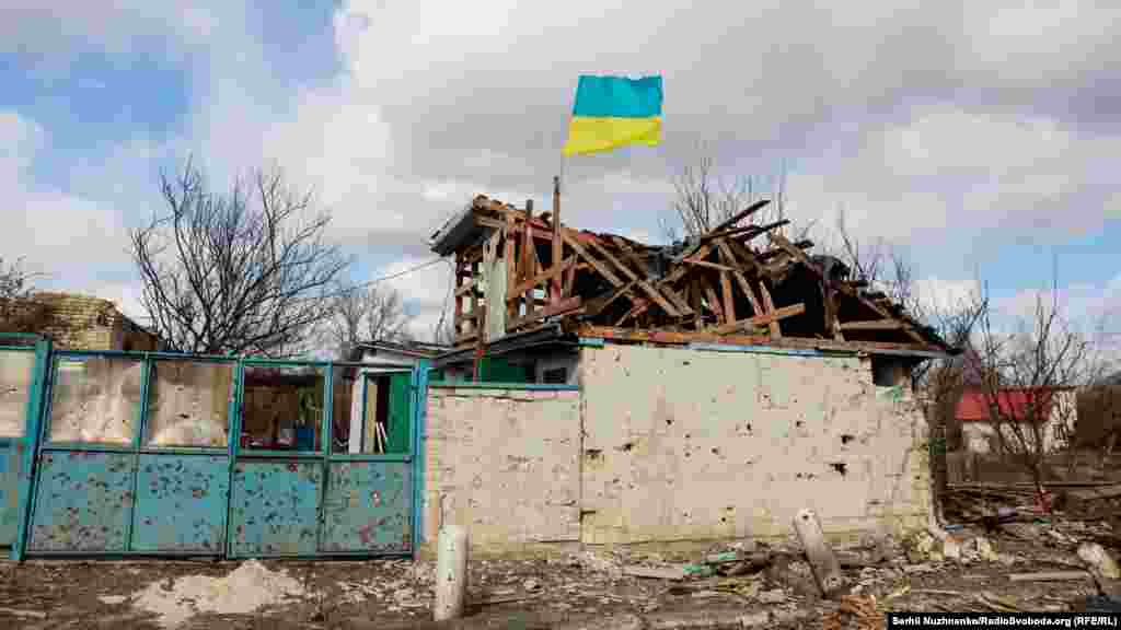 Український прапор майорить на житловому будинку, пошкодженому російськими військами, село Лук‘янівка, Київщина, 27 березня 2022 року