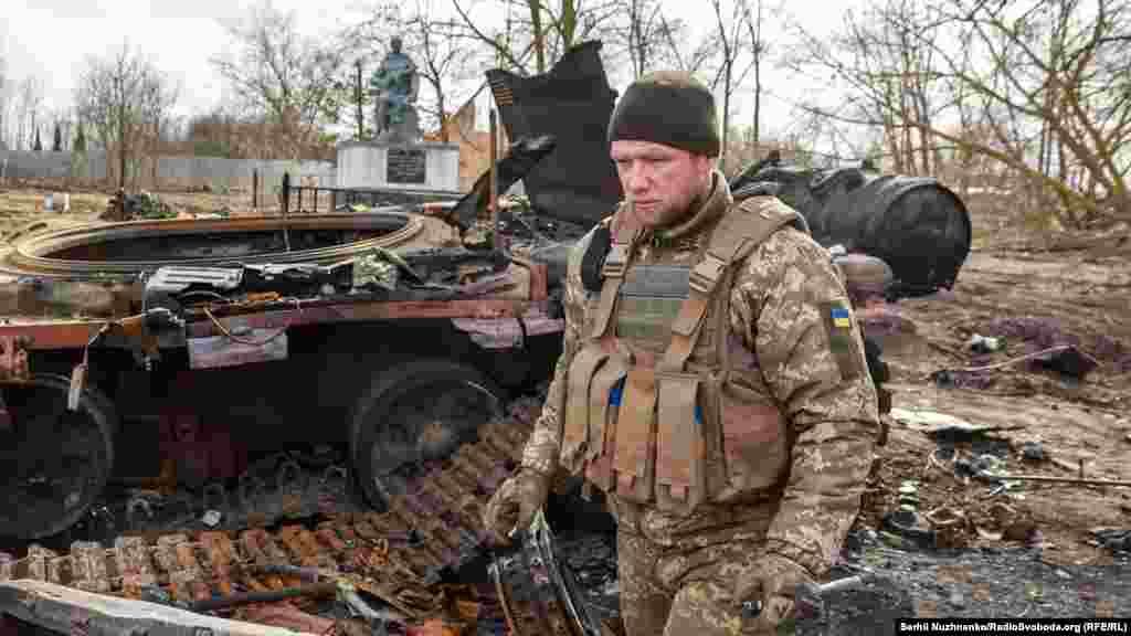 Український військовослужбовець йде біля знищеного російського танка Т-72 у звільненому селі Лук’янівка Київської області, Україна, 27 березня 2022 року