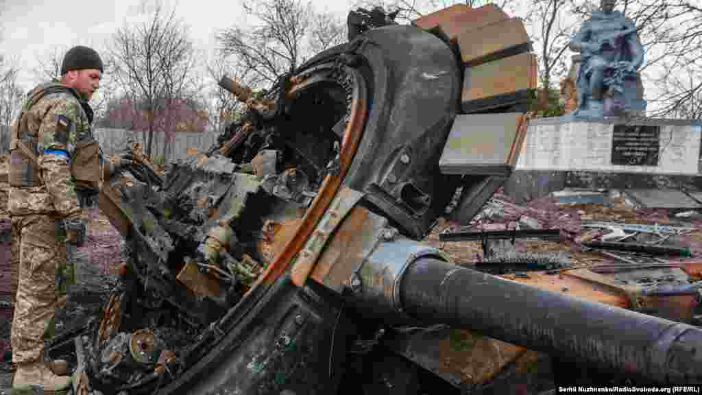 Український військовий оглядає залишки знищеного російського танка у нещодавно звільненому селі Лук'янівка Київської області, Україна, 27 березня 2022 року