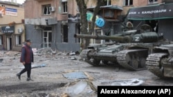 A resident of Mariupol walks past tanks used by pro-Russian separatist forces in May. 