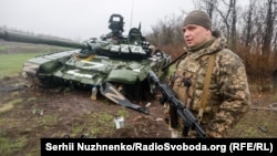 Український військовослужбовець біля пошкодженого російського танка Т-72БЗ під час масштабного вторгнення Росії до України. Донецька область, 13 квітня 2022 року 