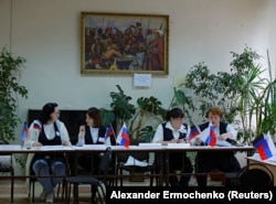 Membrii unei comisii electorale așteaptă alegătorii la o secție de votare în timpul unui așa-zis referendum privind alipirea autoproclamatei Republici Populare Donețk (RPD) la Rusia, în Donețk, Ucraina, 27 septembrie 2022.