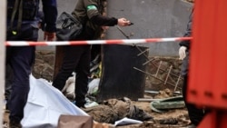 Un polițist ucrainean fotografiază corpul unui civil găsit într-o fântână la o stație de benzină din Buzova.