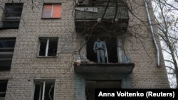 Man looks down on destruction from damaged apartment of residential building in Kherson. (file photo)