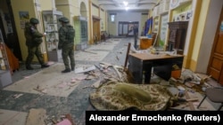 Russian military investigators stand near the body of a person killed by shelling at a youth center in Donetsk on December 6.