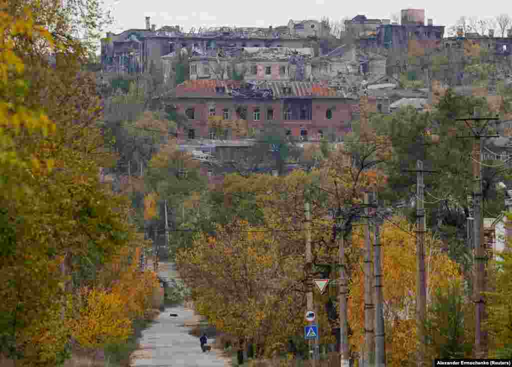 Чоловік тягне візок у напрямку до поруйнованих будівель. Маріуполь, 29 жовтня 2022 року
