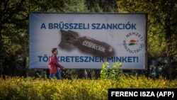 Архивска фотографија - Во Будимпешта на 18 октомври, маж поминува покрај плакат на кој е прикажана бомба, со текст: „Ние сме казнети со санкциите од Брисел“.