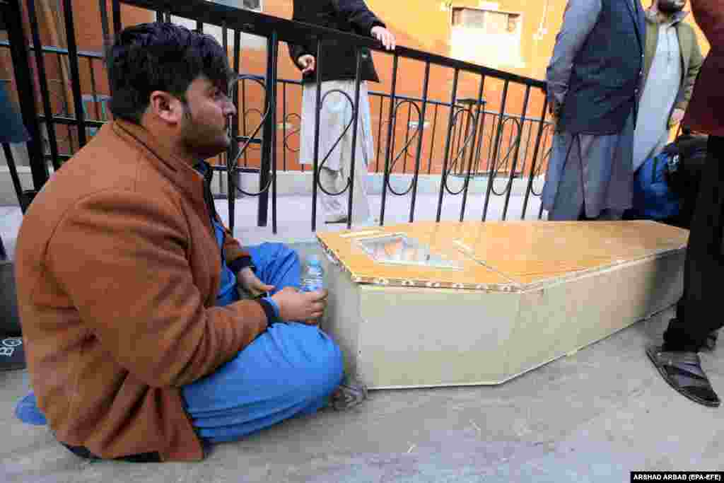 A man sits beside a coffin containing a relative. 