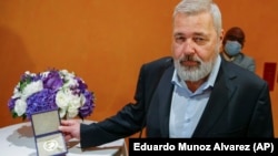 Nobel Peace Prize laureate Dmitry Muratov poses with his 23-carat medal before it is auctioned at the Times Center on June 20 in New York.