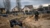 Український військовий біля братської могили з тілами мирних жителів, які, за словами очевидців, були вбиті російськими окупантами у Бучі, 6 квітня 2022 року