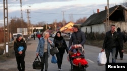 UKRAINE - People walk as they flee from Ukraine to Hungary, after Russia launched a massive military operation against Ukraine, at a border crossing in Tiszabecs, February 27, 2022. 