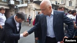 Oleksander Tymoshenko (right) shakes hands with an acquaintance in Kyiv in August.