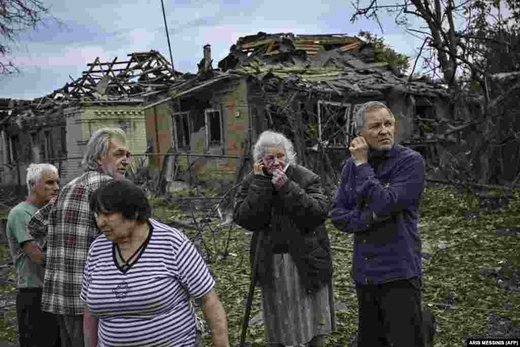 Местные жители собрались на улице после того, как в результате ракетного удара погибла пожилая женщина 