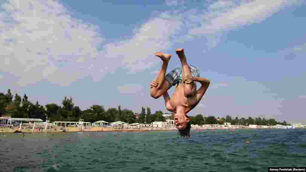 Ныряльщик в Евпатории прыгает с пирса в море 