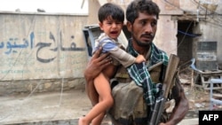An Afghan policeman carries a traumatized child at the site of a suicide car-bombing in front of the Indian consulate in Jalalabad on August 3.