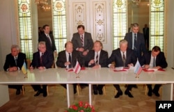 Президент України Леонід Кравчук (другий ліворуч), голова Верховної Ради Білорусі Станіслав Шушкевич (третій ліворуч) та президент Росії Борис Єльцин (другий праворуч) під час підписання Біловезької угоди, яка констатувала припинення існування СРСР. Біловезька Пуща поблизу Берестя (Білорусь), 8 грудня 1991 року