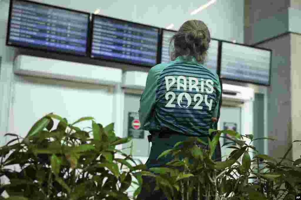 Aeroportul Charles de Gaulle, Paris, Franța – un voluntar de la Olimpiadă privește tabele de sosiri de la aeroport- 19 iulie 2024.
