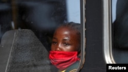 Djevojčica sa zaštitnom maskom gleda kroz prozor autobusa, Južna Afrika, 24. avgusta 2020. 
