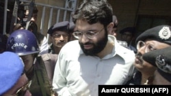 Pakistani police surround handcuffed Omar Sheikh as he comes out of a court in Karachi in 2002.