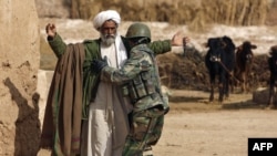 An Afghan soldier frisks a farmer during a patrol in Helmand Province.