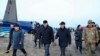 Членови на истражниот комитет и локални функционери поминуваат покрај остатоците од авионот на Азербејџан ерлајнс, кој се урна претходниот ден во близина на Актау во западен Казахстан