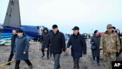 Членови на истражниот комитет и локални функционери поминуваат покрај остатоците од авионот на Азербејџан ерлајнс, кој се урна претходниот ден во близина на Актау во западен Казахстан