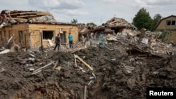 Люди стоять біля зруйнованих житлових будинків на місці російського ракетного удару в Покровську, 24 червня 2024 року