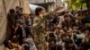 Afghans wait in front of a bank as they try to withdraw money in Kabul on September 12.