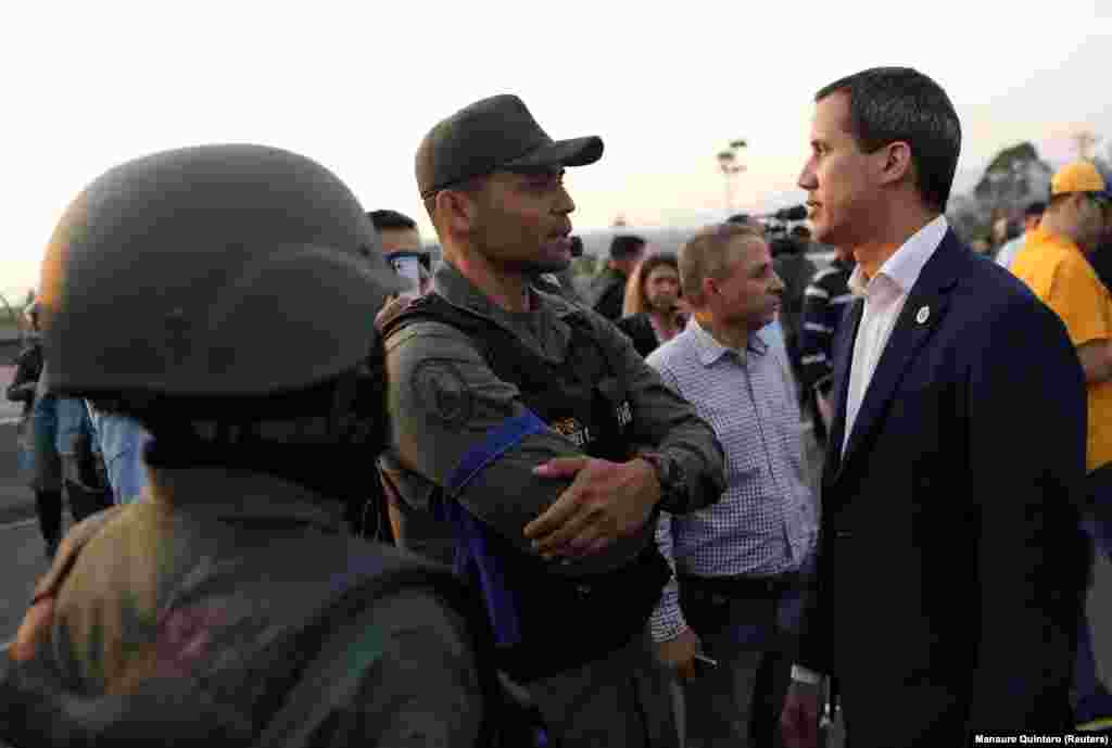 Venezuelan opposition leader Juan Guaido, whose claim to the presidency is backed by the United States and other countries, speaks with a man in uniform near the air base shortly after sunrise in the Venezuelan capital. 