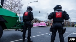 Полиција пред демонстрантите што го блокираа патот протестирајќи против конвенцијата на екстремно десничарската партија Алтернатива за Германија (AfD), во Риеса, Германија, на 11 јануари.