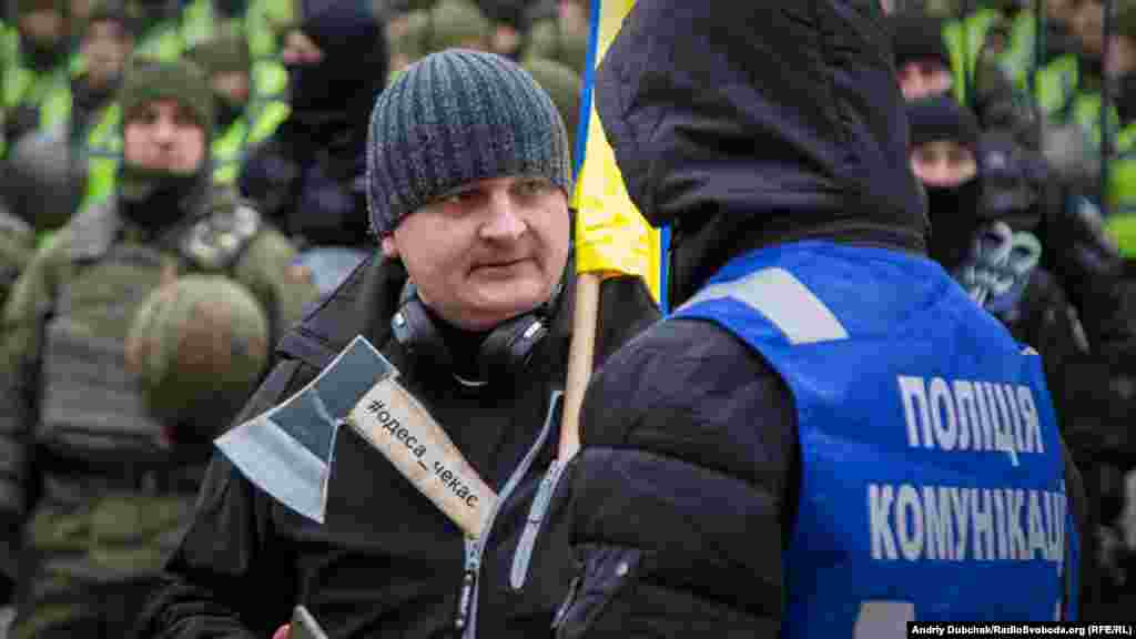 Активіст з «паперовою сокирою» #одеса_чекає спілкується з представником поліції комунікацій під час пікету судового засідання у позові щодо відсторонення від посади міського голови Одеси Геннадія Труханова. Активісти вимагають ув’язнення Труханова. Солом’янський районний суд Києва, 22 лютого 2018 року БІЛЬШЕ ПРО ЦЕ