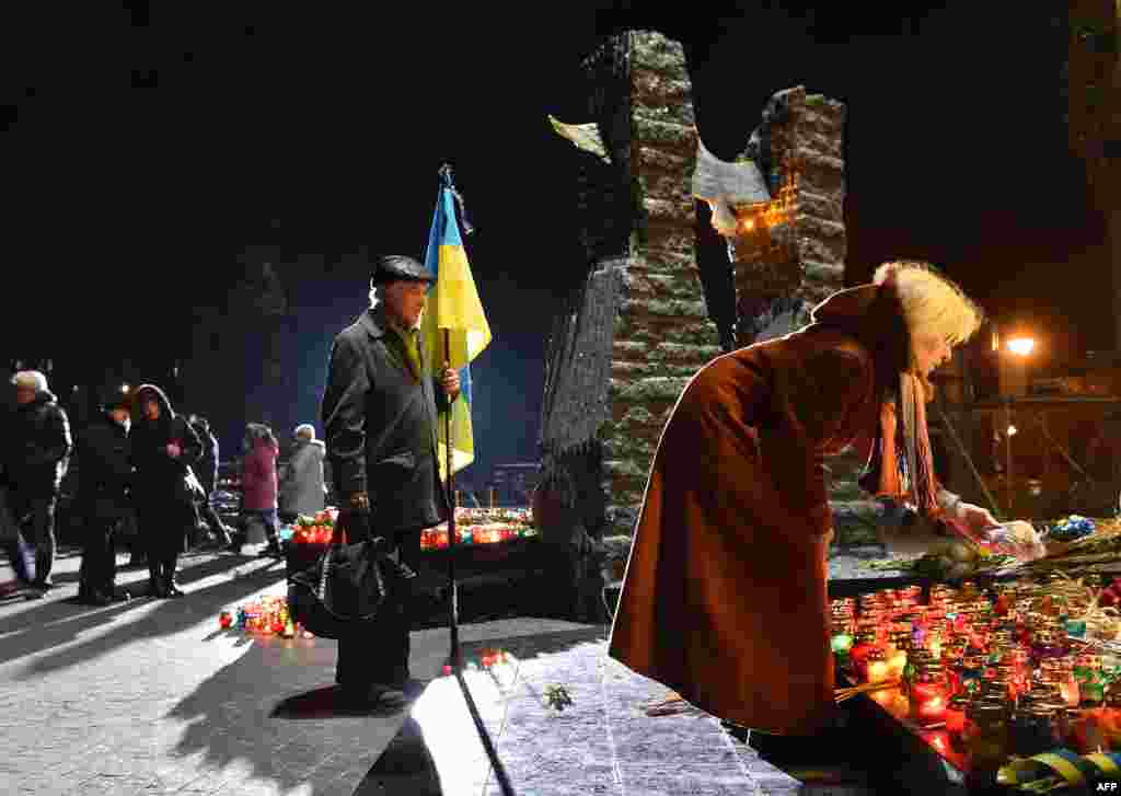 Жінка кладе шматок хліба до Меморіалу жертвам Голодомору у Києві. В суботу, 26 листопада, в Україні вшановують пам’ять жертв голодоморів, в результаті яких загинули мільйони людей. Сьогодні в Україні приспущені державні прапори і скасовані розважальні заходи. Київ, 26 листопада 2016 року