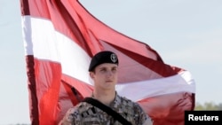 Вайсковец Латвіі з нацыянальным сьцягам
