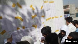 Representatives of Afghan candidates check vote results in front of a polling station in Kabul on September 19.