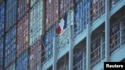 A French flag flies next to containers on a cargo ship owned by shipping company CMA CGM.
