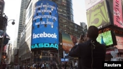 A man takes a picture of a monitor showing a welcoming message for Facebook's listing on the Nasdaq Marketsite prior to the opening bell in New York on May 18.