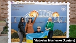 Твір мистецтва у формі великої марки, на якій зображено Кримський міст у вогні. Центр Києва, 8 жовтні 2022 року