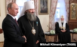 Очільник Росії Володимир Путін (ліворуч) під час вручення державної нагороди Росії наміснику Києво-Печерської лаври митрополиту УПЦ (Московського патріархату) Павлу (Петру Лебідю) (другий зліва). Праворуч – патріарх Московський Кирило. Київ, 27 липня 2013 року