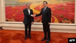 Chinese Vice Prime Minister Ding Xuexiang (right) welcomes Iranian Foreign Minister Abbas Araqchi in Beijing on April 23.