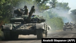Українські військовослужбовці їдуть на танках по дорозі на Луганщині, 21 червня 2022 року